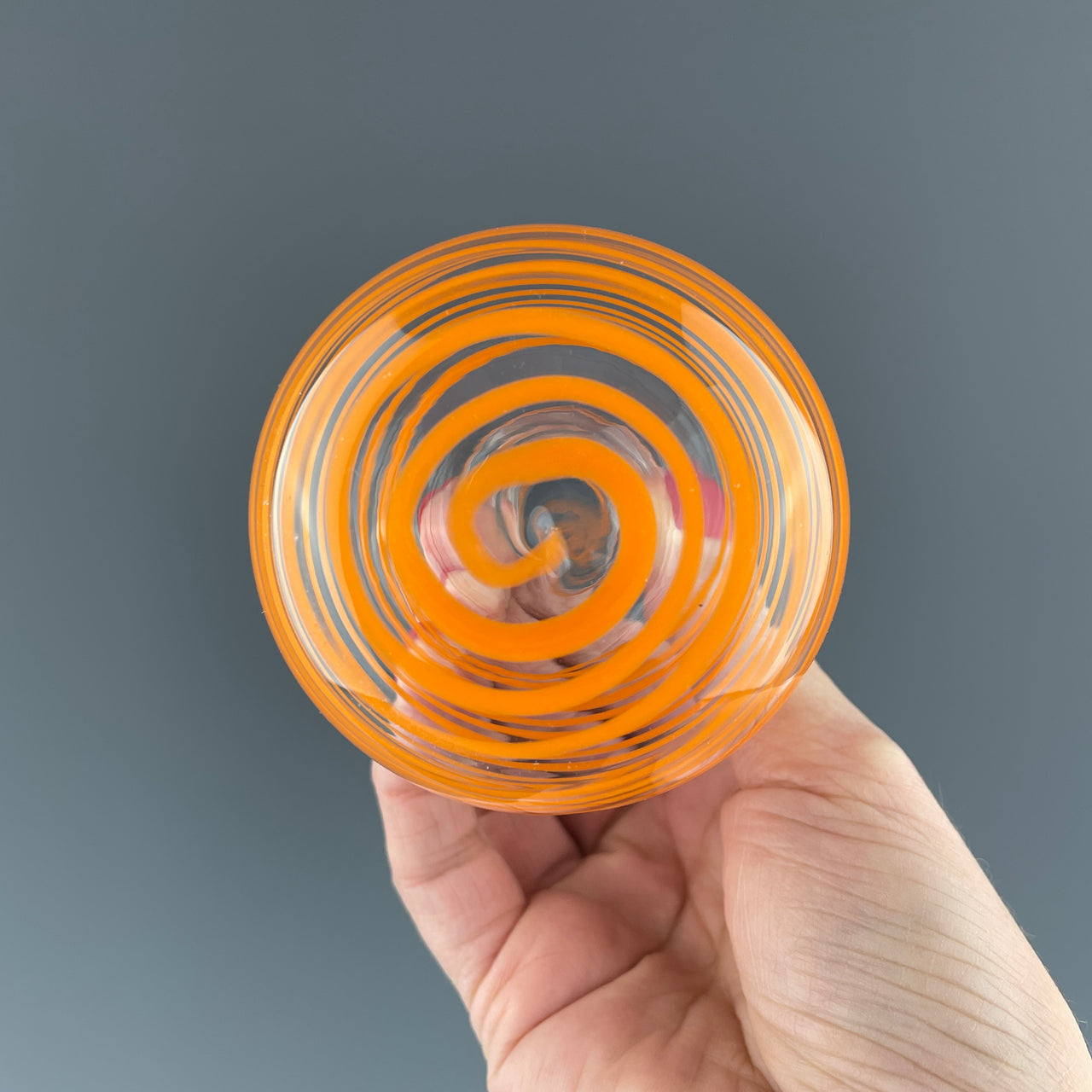 bottom of a glass vase with orange swirls