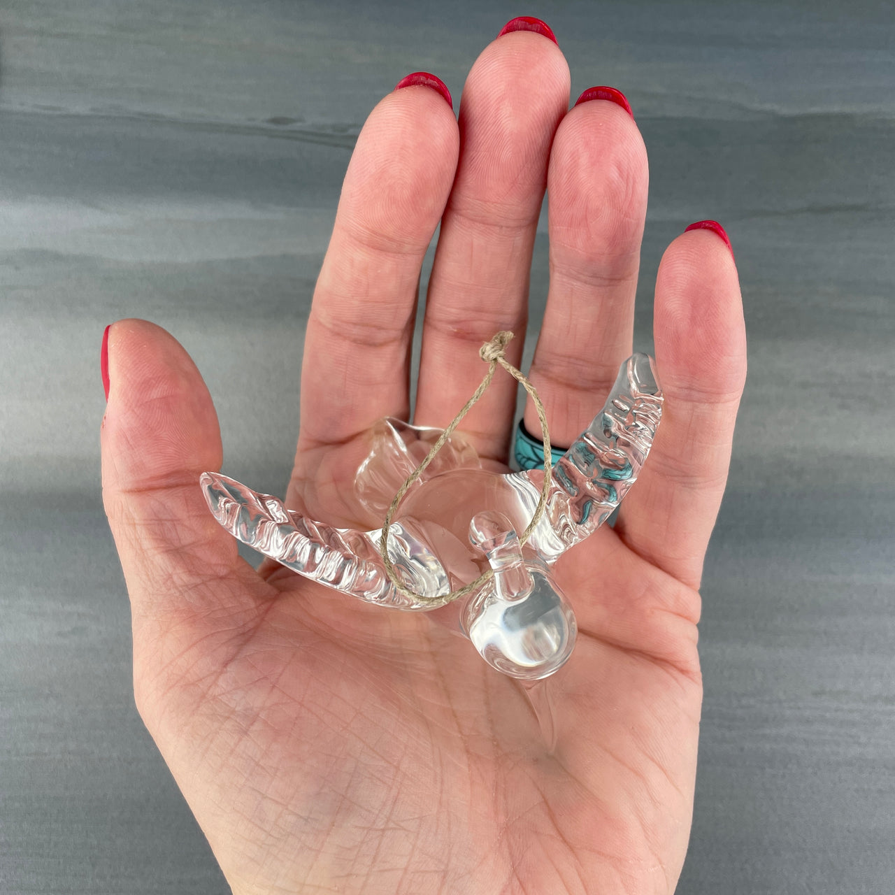 glass hummingbird sitting in the palm of a hand